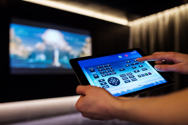 Person using a tablet to control a home cinema theater system.