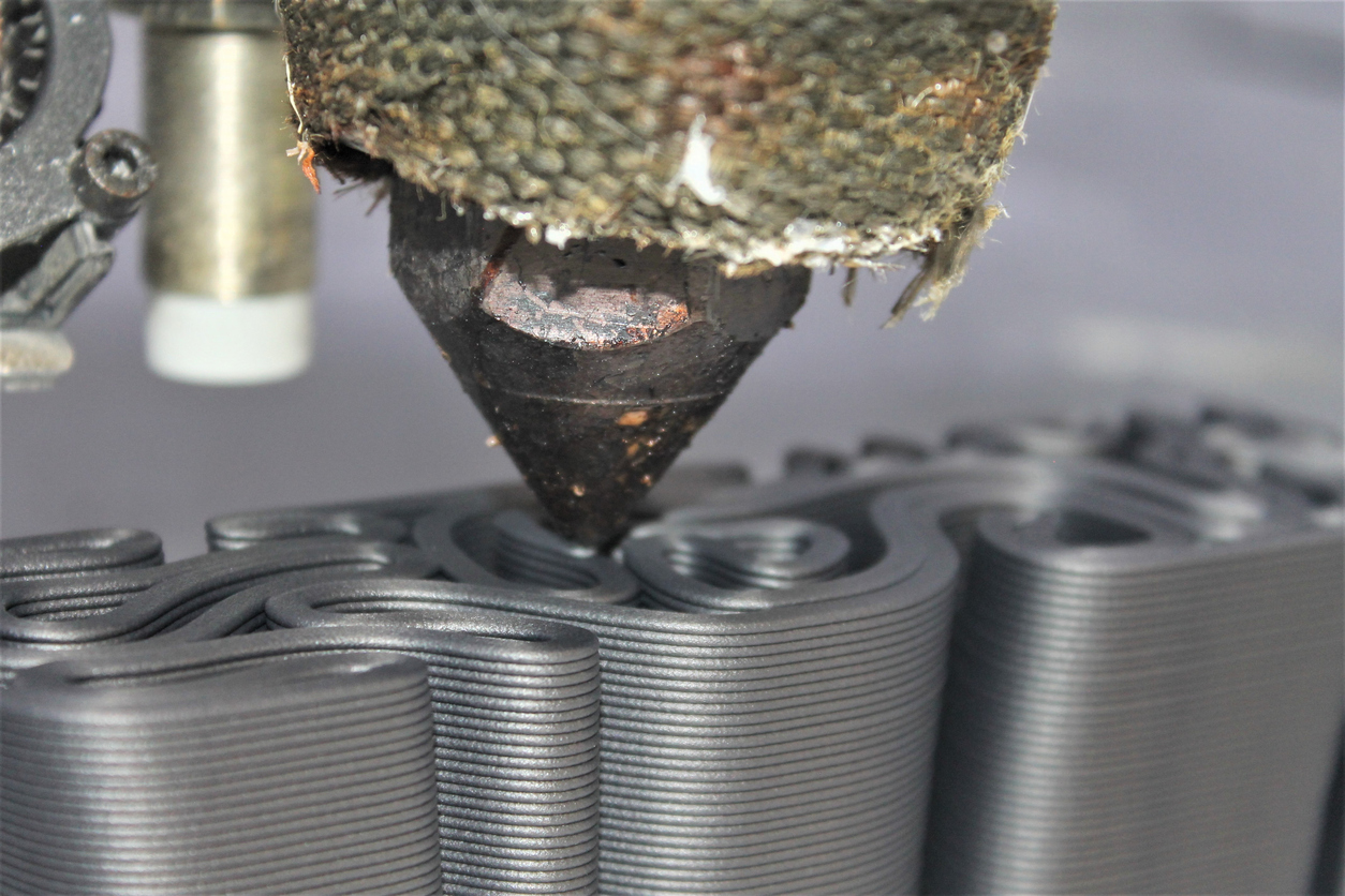 Close-up of a 3D printer injection head forming a part.