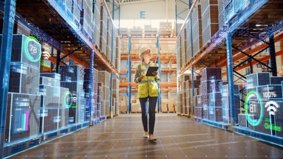 A warehouse worker walks down the aisle of an industrial workplace with a tablet with smart technology overlays on the stock shelves.