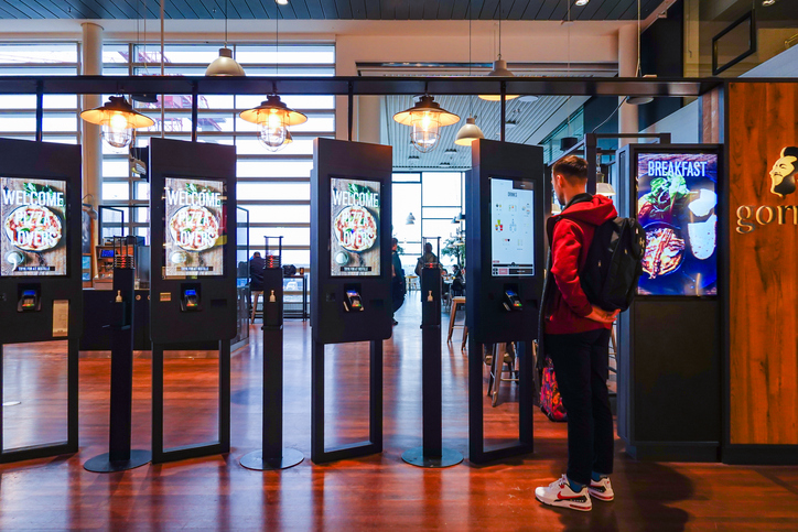 A man orders food from display screens at a restaurant.