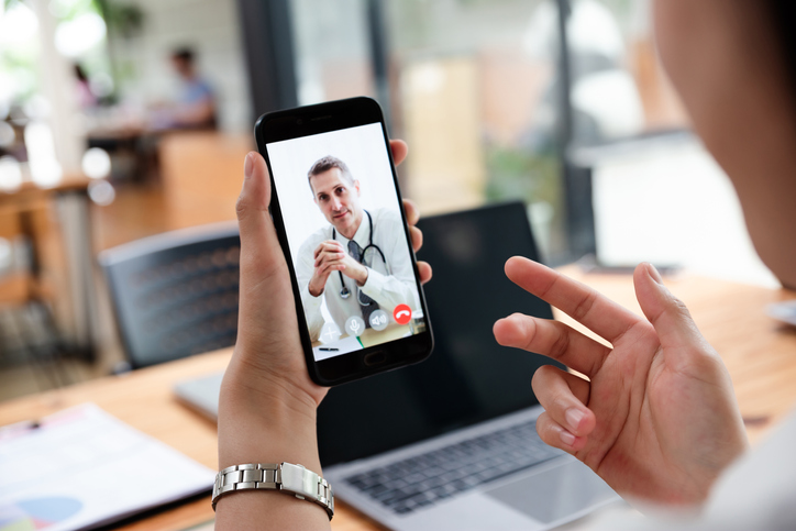 Businesswoman talking with doctor online from office. Medical specialist consulting patient on mobile phone. Healthcare and medical concept.