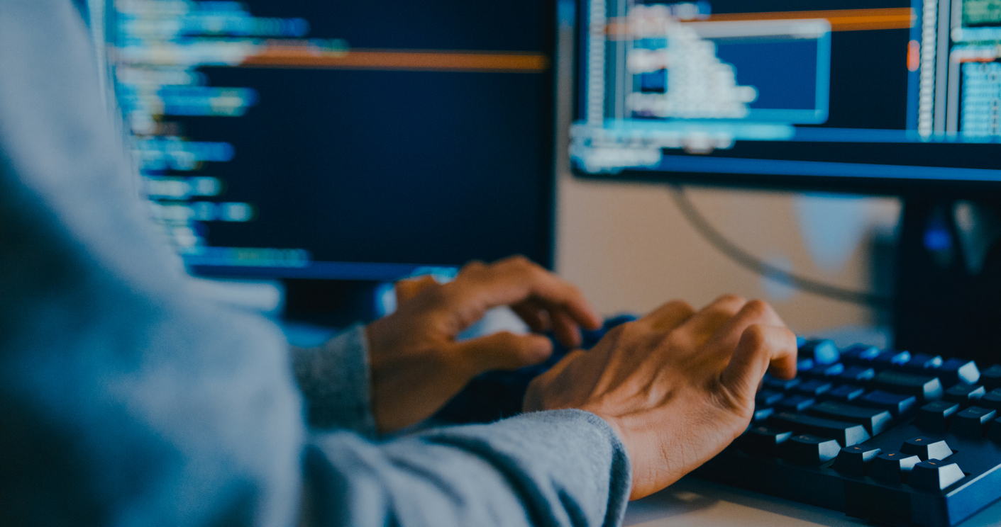 Developer working at a desktop computer typing code.