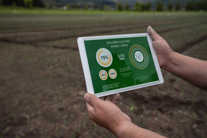 Close-up on a farmer using an app on a tablet computer to track the productivity of his soil for harvesting - agriculture concepts.