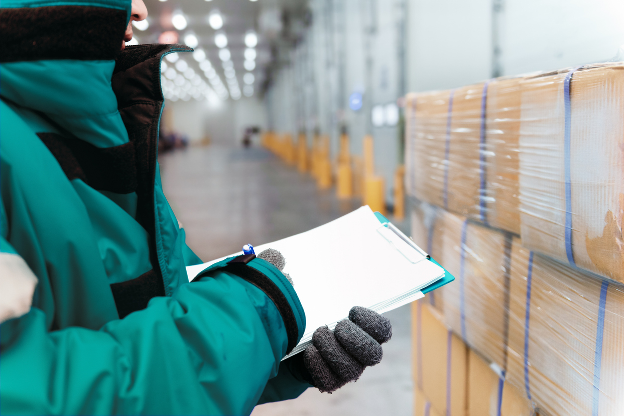 Worker inspecting goods in a cold storage warehouse for export and import logistics.