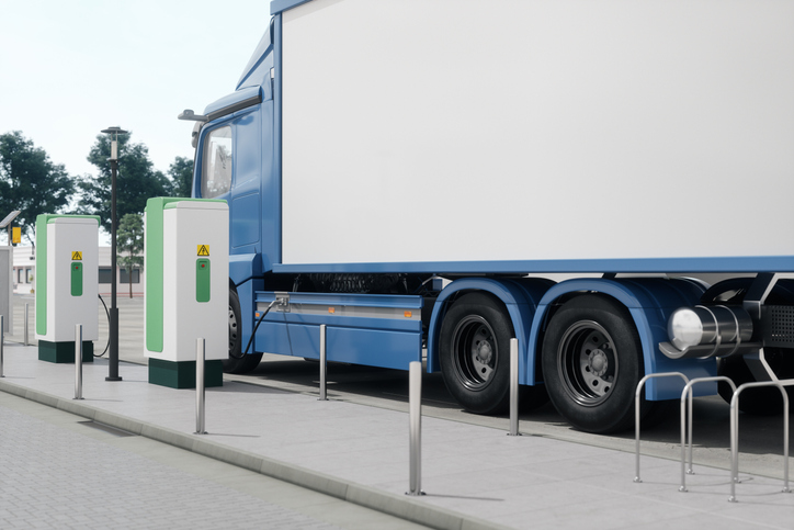 Electric truck charging at a charging station.