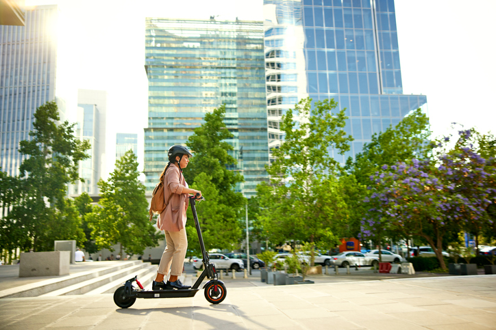 Full length side view of environmentally aware professional in work attire, safety helmet and backpack, beginning her commute home