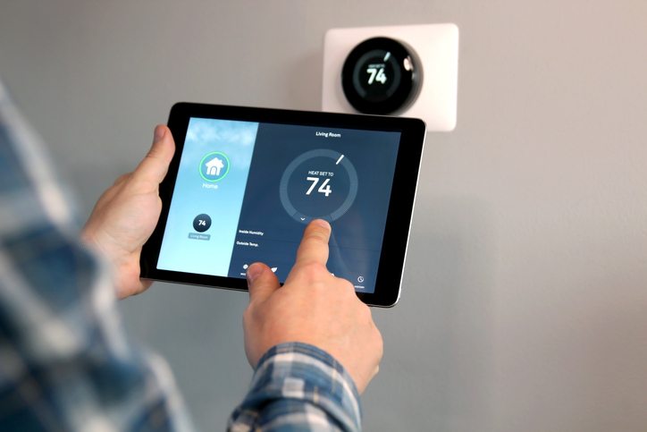 Man is Adjusting a temperature using a tablet with smart home app in modern living room.