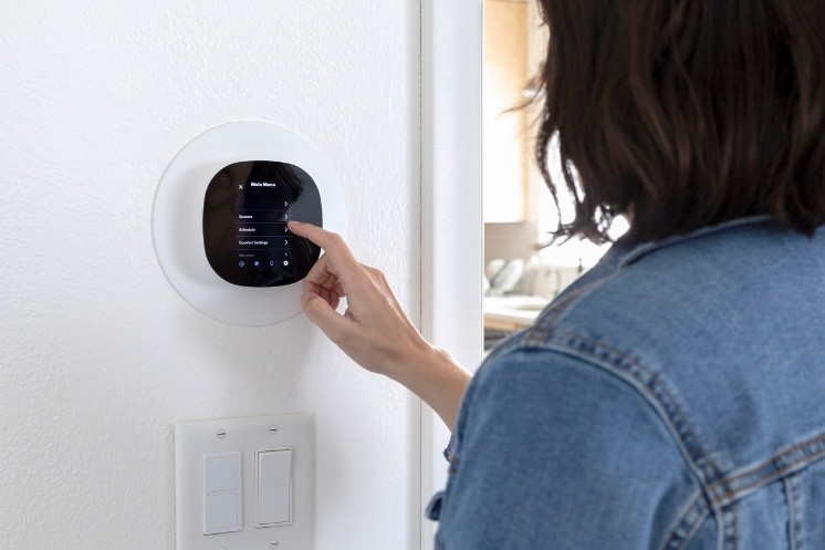 Person programming a smart thermostat at home