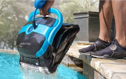 Person holding a Maytronics robotic pool cleaner above a swimming pool.